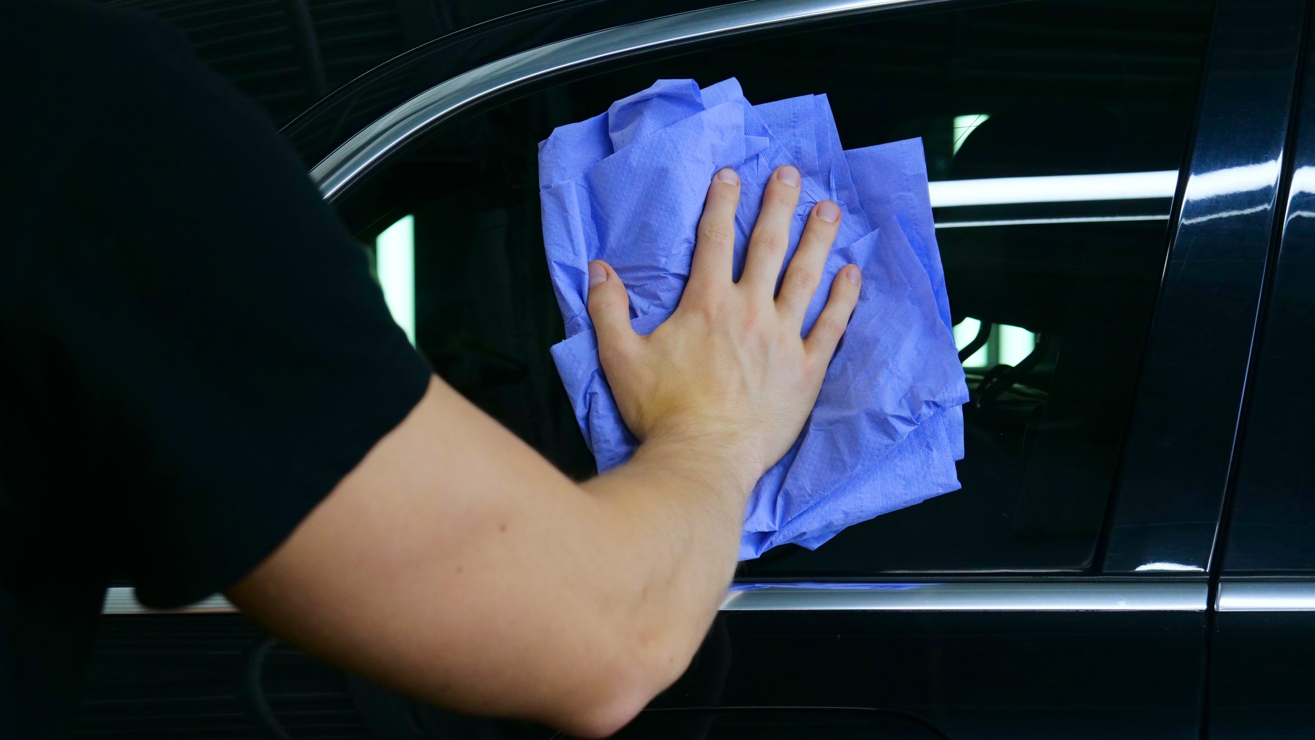 Professional car washer wipes and dries window after car washing